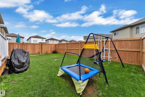 Private backyard featuring a wooden privacy fence, green lawn, and an exterior deck with white railings - 2419 15 Avenue, Edmonton, AB 