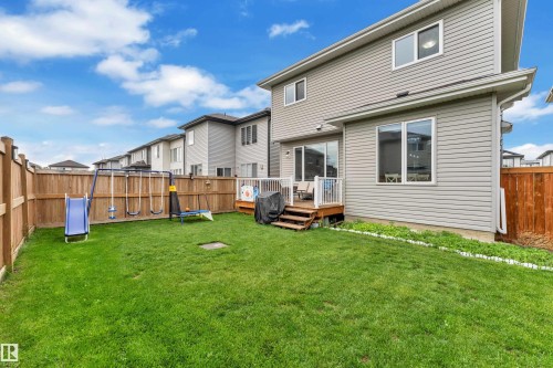 Expansive backyard featuring a manicured lawn, full wood fencing, and a multi-level wood deck - 2419 15 Avenue, Edmonton, AB 