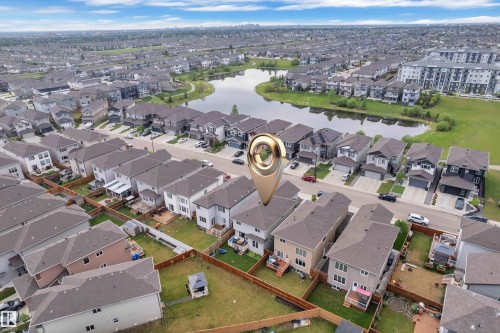 Aerial perspective showcasing a residential development featuring single-family homes and multi-story buildings surrounding a central pond - 2419 15 Avenue, Edmonton, AB 