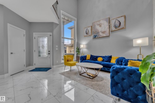 Spacious living area featuring a two-story ceiling, tall windows, and large format tile flooring - 2419 15 Avenue, Edmonton, AB 