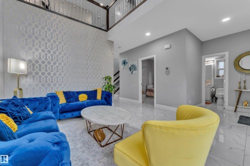 Two-story living area featuring a patterned accent wall, recessed lighting, and a second-story balcony with metal railings - 2419 15 Avenue, Edmonton, AB 