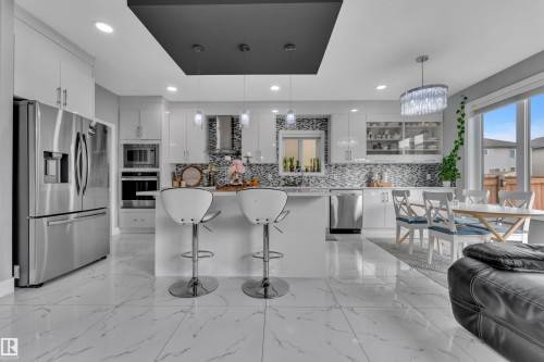 Modern kitchen featuring white cabinetry, stainless steel appliances, and a central island with countertop seating - 2419 15 Avenue, Edmonton, AB 