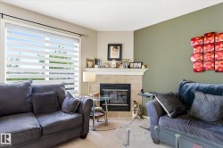 Living area featuring a tiled fireplace with mantel, large window with horizontal blinds, and neutral-toned wall paint - 