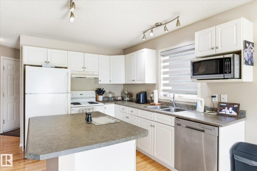 Kitchen featuring white cabinetry, track lighting, and wood-finish flooring - 37 4020 21 Street, Edmonton, AB 