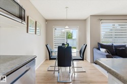 Open concept dining area featuring wood-finish flooring, a contemporary pendant light fixture, and a sliding glass door with horizontal blinds - 