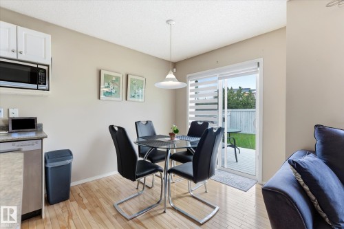 Dining area with wood-finish flooring and a contemporary pendant light fixture - 37 4020 21 Street, Edmonton, AB 