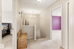 Upper-level hallway featuring neutral wall paint, light-colored carpeting, and white trim - 