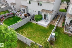 Private backyard featuring a manicured lawn, a grey wooden fence, and a dedicated patio area - 