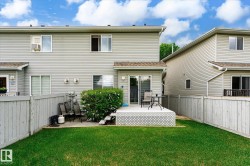 Fenced backyard featuring a manicured lawn, a raised deck with lattice skirting, and a sliding glass door for patio access - 