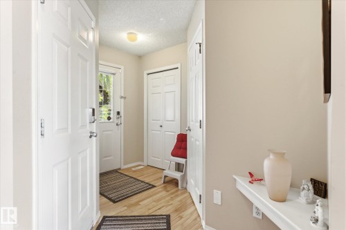 Front entry foyer with wood-finish flooring, light tan walls, and white trim - 37 4020 21 Street, Edmonton, AB 
