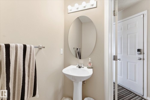 Pedestal sink with chrome-finish faucet, illuminated by a multi-bulb vanity light fixture - 37 4020 21 Street, Edmonton, AB 
