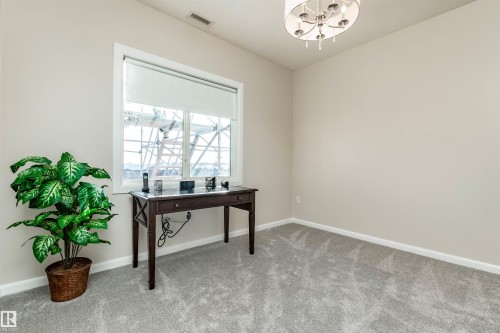 Neutral-toned room featuring a single window with a roller shade, light gray carpeting, and a ceiling-mounted chandelier - 439 300 Palisades Way, Sherwood Park, AB - Indoor Photo Showing Other Room