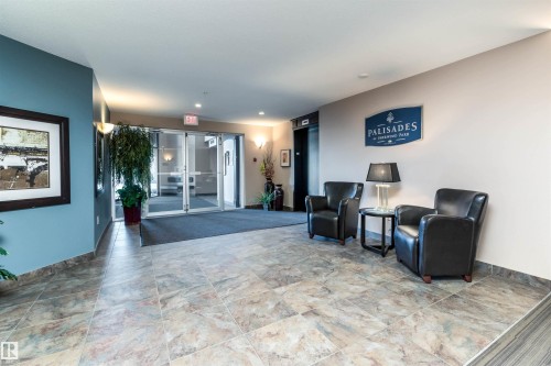 Spacious lobby featuring large format tile flooring, a seating area with two dark leather armchairs, and an integrated elevator access point - 439 300 Palisades Way, Sherwood Park, AB - Indoor