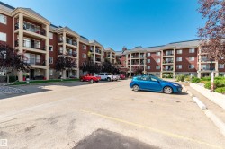 Multi-story building featuring brick and stucco exterior, individual balconies with black railings, and mature landscaping - 