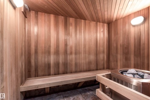 Built-in sauna featuring wood-paneled walls and ceiling, a wooden bench, and a stainless steel heater with volcanic rocks - 439 300 Palisades Way, Sherwood Park, AB - Indoor Photo Showing Other Room