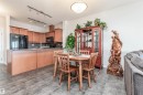 Open-concept kitchen and dining area featuring wood-finish cabinetry, black appliances, track lighting, and tile flooring - 439 300 Palisades Way, Sherwood Park, AB  - Indoor 