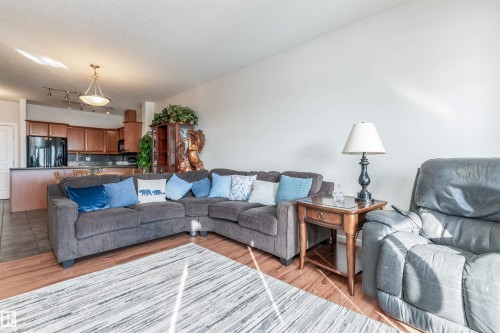 Open-concept living area featuring wood-finish flooring, a kitchen island, and a pendant light fixture - 439 300 Palisades Way, Sherwood Park, AB - Indoor Photo Showing Living Room