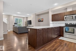 Modern kitchen featuring dark wood cabinetry, white countertops, stainless steel appliances, and a white subway tile backsplash - 