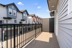 Private balcony featuring an exterior wall with horizontal siding and a black metal railing - 