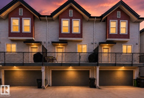 Multi-level townhouse exterior featuring light-toned horizontal siding, red shake accents, and dark pitched roofs - 30 6075 Schonsee Way, Edmonton, AB 