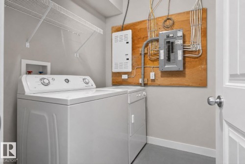 Dedicated laundry area featuring a washer and dryer, integrated wire shelving, and a neutral wall color - 30 6075 Schonsee Way, Edmonton, AB 
