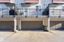 Exterior featuring multiple attached garages with gray panel doors and a concrete driveway - 30 6075 Schonsee Way, Edmonton, AB 
