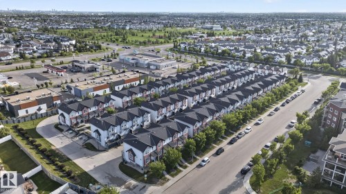 Aerial perspective showcasing rows of contemporary townhomes with dark shingled roofs and light-colored siding - 30 6075 Schonsee Way, Edmonton, AB 