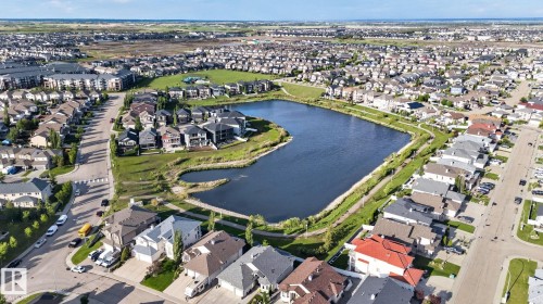 Residential area featuring a central pond with surrounding green spaces and walking paths - 30 6075 Schonsee Way, Edmonton, AB 