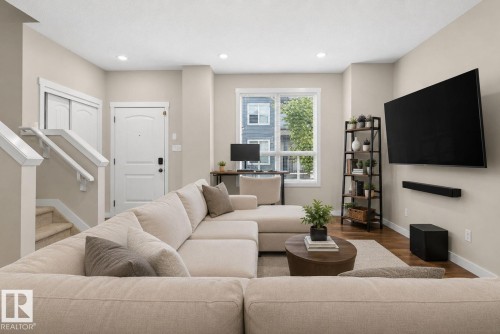 Open-concept living area with wood-finish flooring, recessed lighting, and a neutral color palette - 30 6075 Schonsee Way, Edmonton, AB 