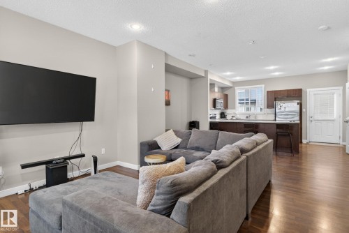 Open-concept living area featuring wood-finish flooring, recessed lighting, and light-toned wall paint - 30 6075 Schonsee Way, Edmonton, AB 