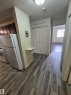 Wood-finish plank flooring extends through the hallway, complemented by a recessed ceiling light fixture - 401 10615 110 Street, Edmonton, AB 