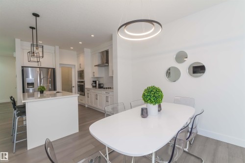 Modern kitchen and dining area featuring light wood-finish flooring - 15168 16 Street Nw, Edmonton, AB 