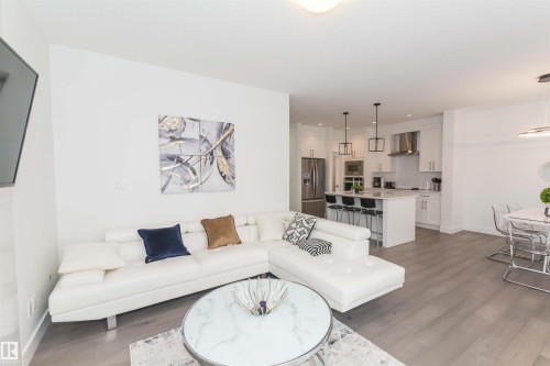 Open-concept living space featuring wood-finish flooring, recessed lighting, and a white color palette - 15168 16 Street Nw, Edmonton, AB 