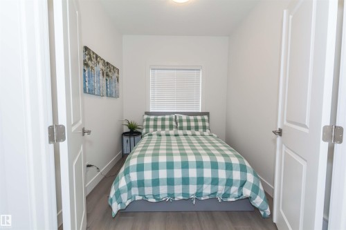 Bright interior space featuring a single window with horizontal blinds, recessed lighting, and wood-finish flooring - 15168 16 Street Nw, Edmonton, AB 