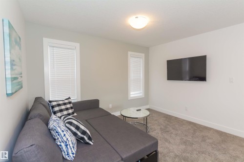 Carpeted living space featuring light gray wall paint, window blinds, white trim, and a flush mount ceiling light fixture - 15168 16 Street Nw, Edmonton, AB 