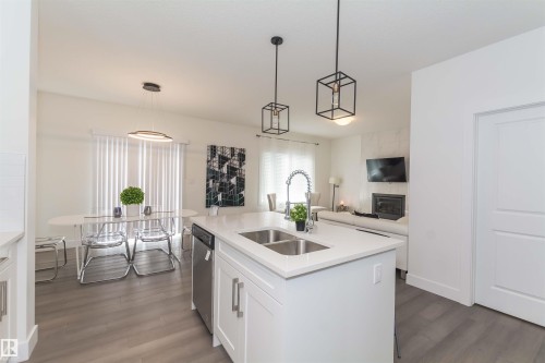 Kitchen island featuring a dual stainless steel sink, gooseneck faucet, and integrated dishwasher - 15168 16 Street Nw, Edmonton, AB 