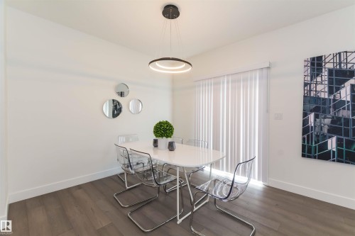 Contemporary dining area featuring wood-finish flooring, a modern circular chandelier, and a large vertical window blind - 15168 16 Street Nw, Edmonton, AB 