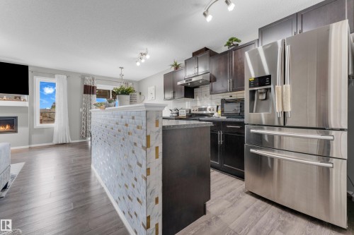 Kitchen featuring stainless steel appliances, dark wood-finish cabinetry, and a subway tile backsplash - 1532 33B Street, Edmonton, AB 