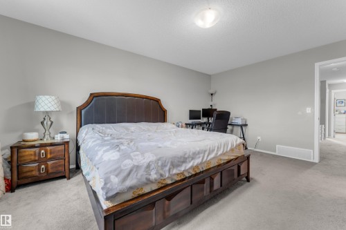 Spacious bedroom featuring light neutral wall tones and a textured ceiling - 1532 33B Street, Edmonton, AB 