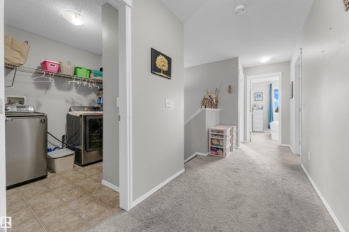 Dedicated laundry space with neutral tile flooring, wire shelving, and overhead lighting - 1532 33B Street, Edmonton, AB 