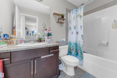 Bathroom featuring a dark wood-finish vanity with a light speckled countertop, an undermount sink, and a chrome faucet - 1532 33B Street, Edmonton, AB 