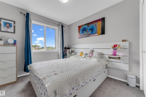 Bedroom featuring a large window, soft gray wall paint, and gray carpet flooring - 1532 33B Street, Edmonton, AB 