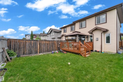 Expansive backyard featuring a manicured lawn, full-height privacy fencing, and a multi-level wood deck - 1532 33B Street, Edmonton, AB 