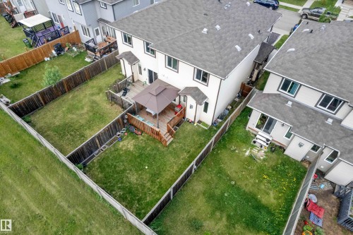 Expansive fenced backyard featuring a multi-level wood deck, a covered patio area, and a large grass lawn - 1532 33B Street, Edmonton, AB 