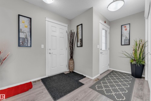 Entryway featuring two white panel doors, wood-finish flooring, and light gray wall paint - 1532 33B Street, Edmonton, AB 
