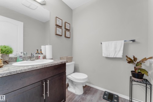 Bathroom featuring a dark wood-finish vanity with dual cabinet doors, a drop-in sink, and a speckled countertop - 1532 33B Street, Edmonton, AB 
