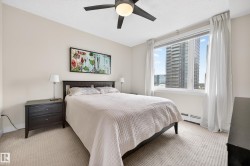 Wall-to-wall textured carpeting, a large window with white trim, and a ceiling fan with integrated lighting - 