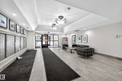 Spacious building entrance featuring light-toned tile flooring, recessed ceiling lighting, and decorative wall art - 