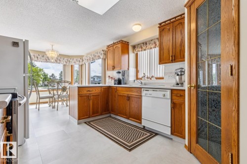 Kitchen area featuring wood cabinetry, white countertops, a bay window dining nook, and a new flooring - 5131 152A Avenue, Edmonton, AB 