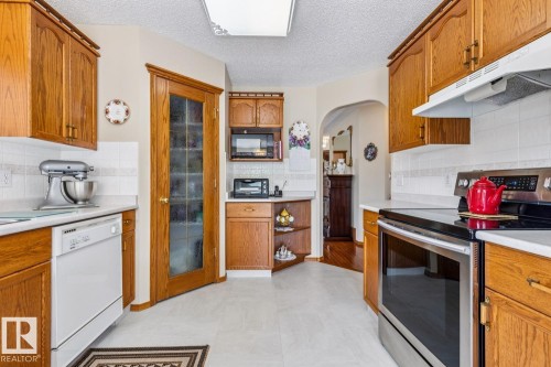 Kitchen featuring wood-finish cabinetry, white countertops, white subway tile backsplash, and light-toned flooring - 5131 152A Avenue, Edmonton, AB 